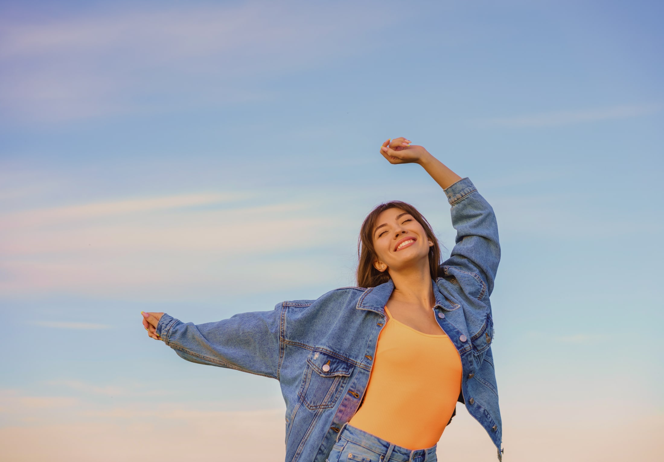 Young woman expresses happiness with her body and eyes sky blue background