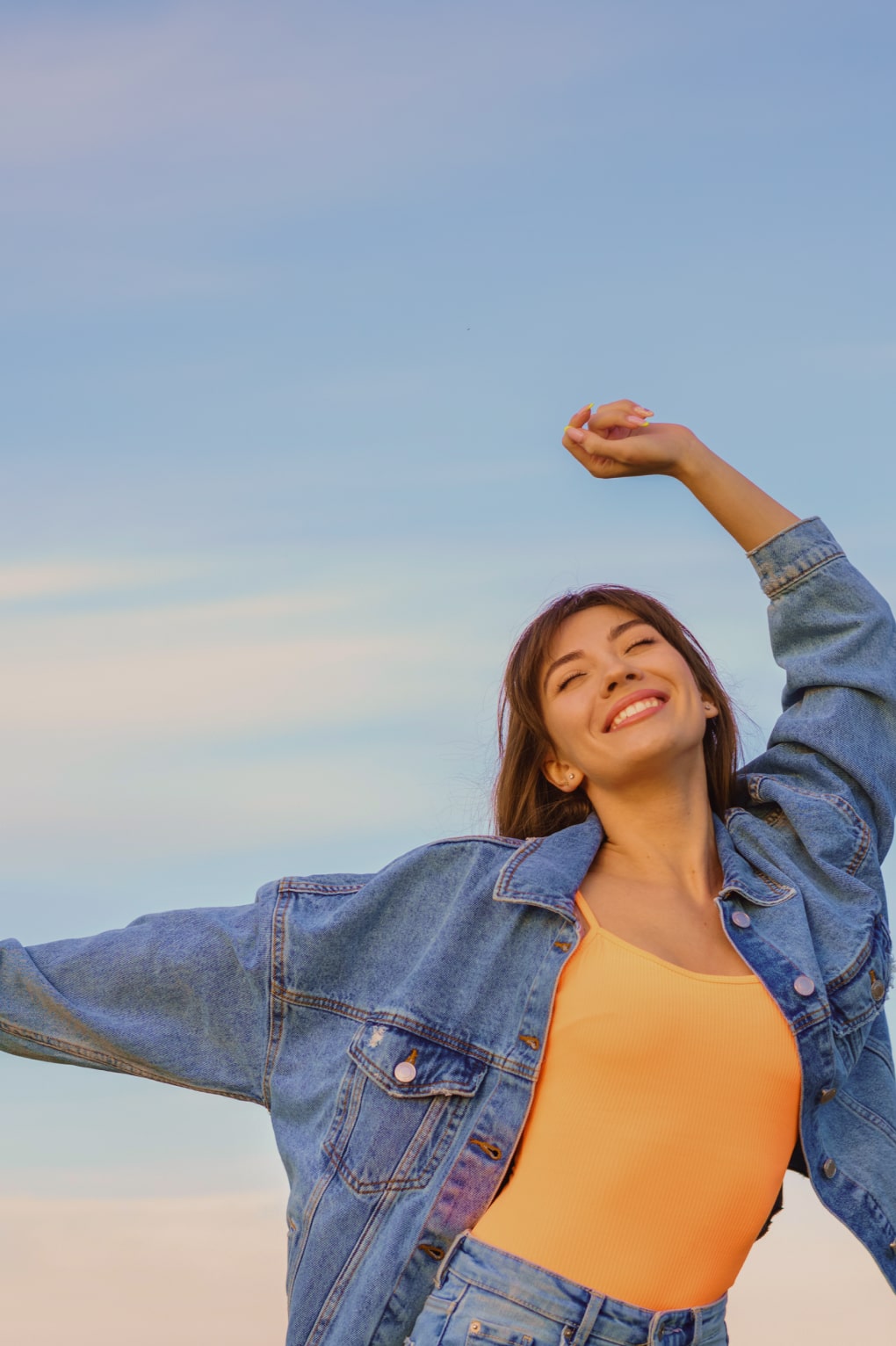 Young woman expresses happiness with her body and eyes sky blue background